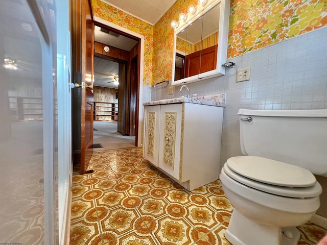 bathroom with vanity, toilet, and tile walls