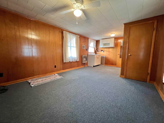 interior space featuring carpet flooring, heating unit, ceiling fan, and wood walls