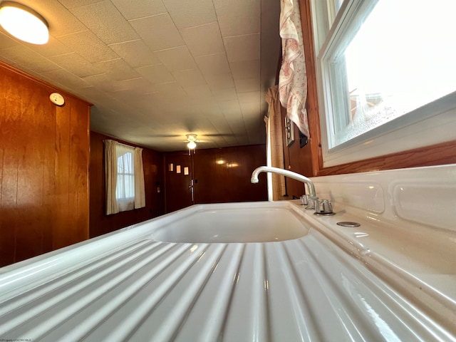 interior details featuring ceiling fan and wooden walls