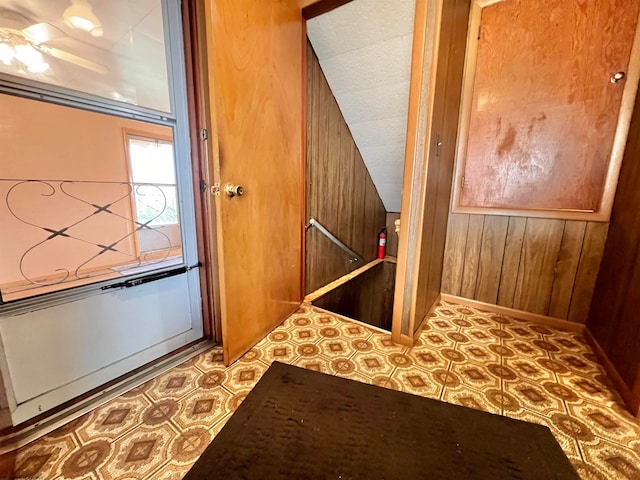 interior space with ceiling fan and wooden walls