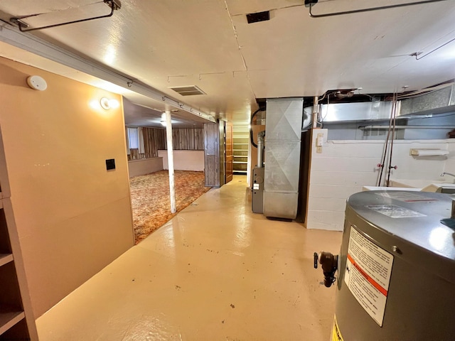 basement featuring electric water heater and heating unit