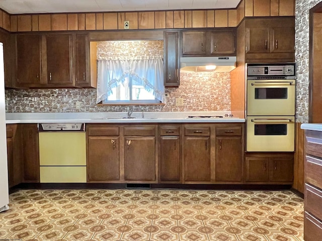 kitchen with backsplash, dark brown cabinets, sink, and white appliances