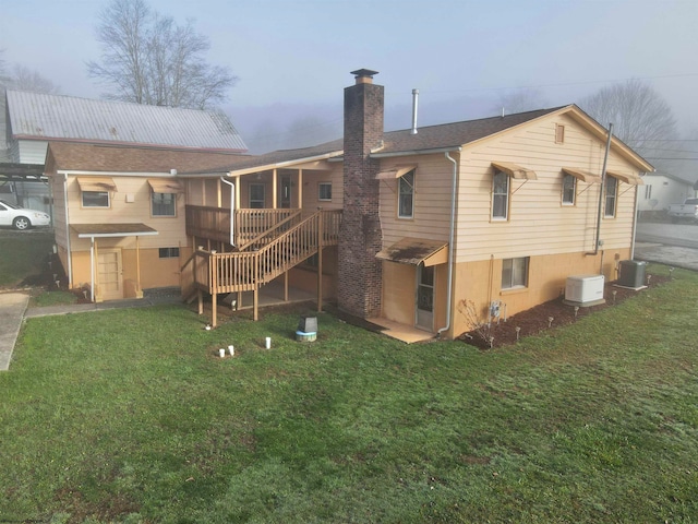 rear view of property with central air condition unit and a yard