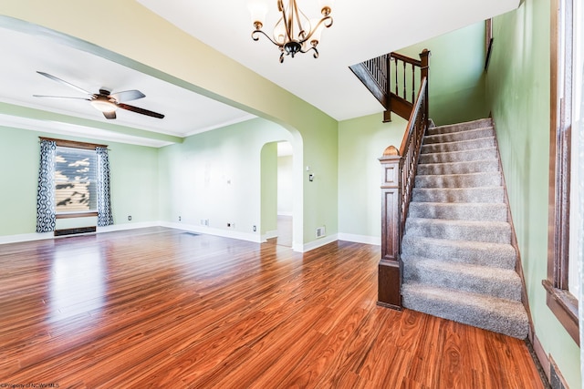 interior space featuring hardwood / wood-style floors, ceiling fan with notable chandelier, and ornamental molding