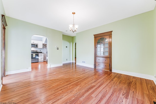 empty room featuring a chandelier and light hardwood / wood-style floors