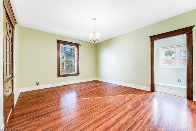 unfurnished room with a chandelier and light hardwood / wood-style floors