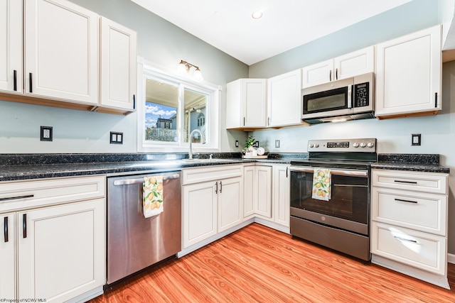 kitchen featuring white cabinetry, sink, stainless steel appliances, and light wood-type flooring