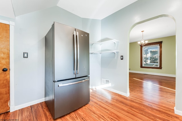 kitchen with hardwood / wood-style floors, a notable chandelier, hanging light fixtures, and stainless steel refrigerator