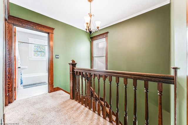 hall featuring light carpet, ornamental molding, and an inviting chandelier