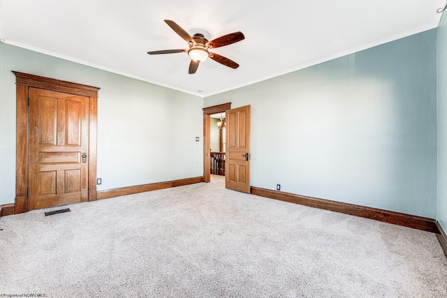 empty room featuring ceiling fan, crown molding, and carpet floors