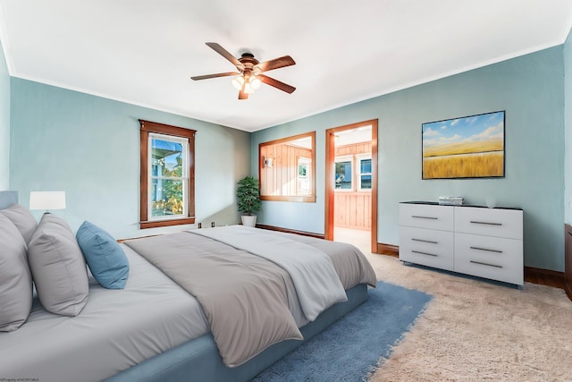 carpeted bedroom featuring crown molding, ensuite bath, and ceiling fan