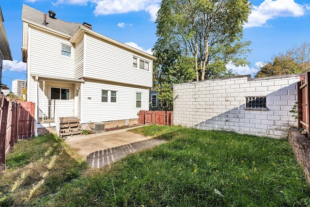 rear view of property with central AC unit, a yard, and a patio