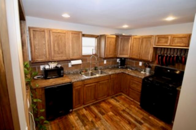 kitchen with dark hardwood / wood-style flooring, sink, and black appliances