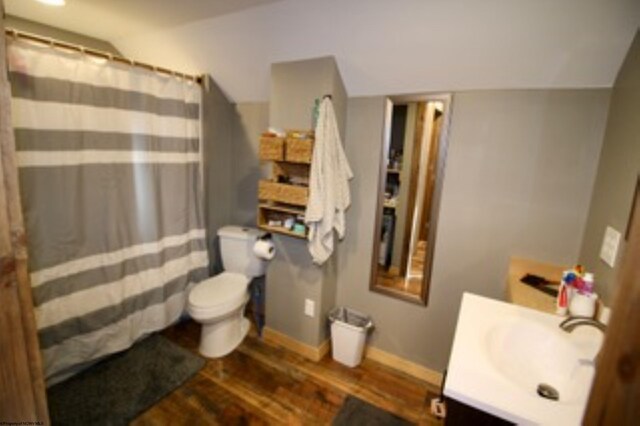 bathroom with hardwood / wood-style floors, vanity, toilet, and lofted ceiling