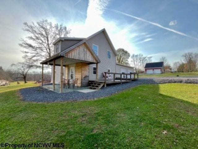 back of property with a wooden deck, a patio area, and a yard