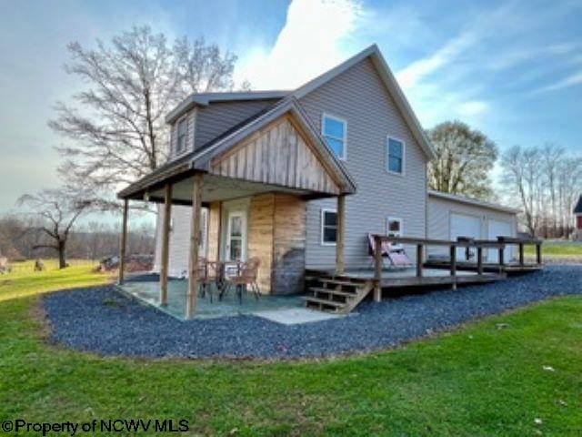 rear view of property featuring a lawn, a wooden deck, and a patio area