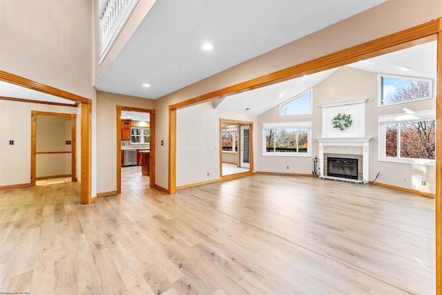 unfurnished living room with light hardwood / wood-style floors, high vaulted ceiling, and a tiled fireplace