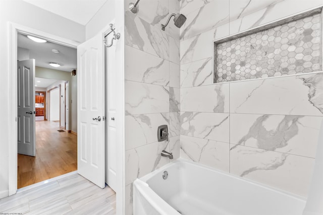 bathroom featuring wood-type flooring and tiled shower / bath