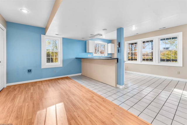 kitchen featuring light wood-type flooring, white cabinetry, and a wealth of natural light