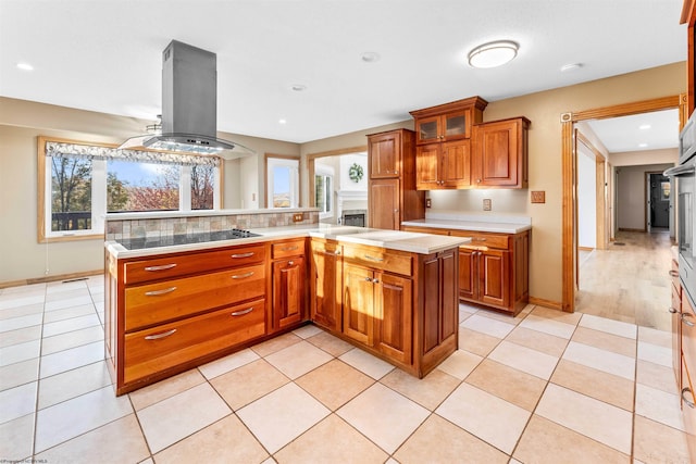 kitchen featuring black electric stovetop, plenty of natural light, island range hood, and kitchen peninsula