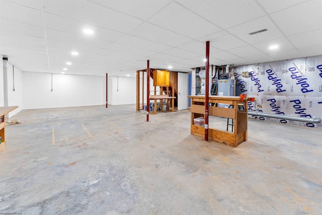 basement with a paneled ceiling and water heater