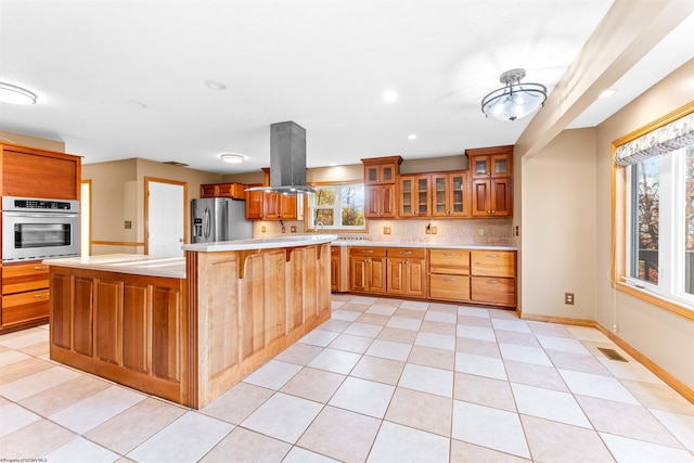 kitchen with island exhaust hood, stainless steel appliances, a kitchen island, and plenty of natural light