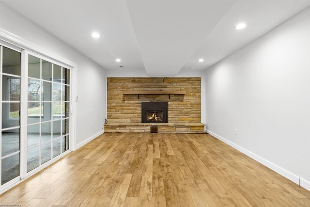 unfurnished living room with a stone fireplace and light wood-type flooring