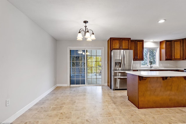 kitchen with a notable chandelier, plenty of natural light, stainless steel fridge, and pendant lighting