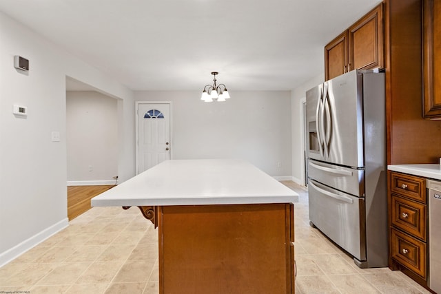 kitchen with pendant lighting, a center island, an inviting chandelier, light tile patterned floors, and appliances with stainless steel finishes