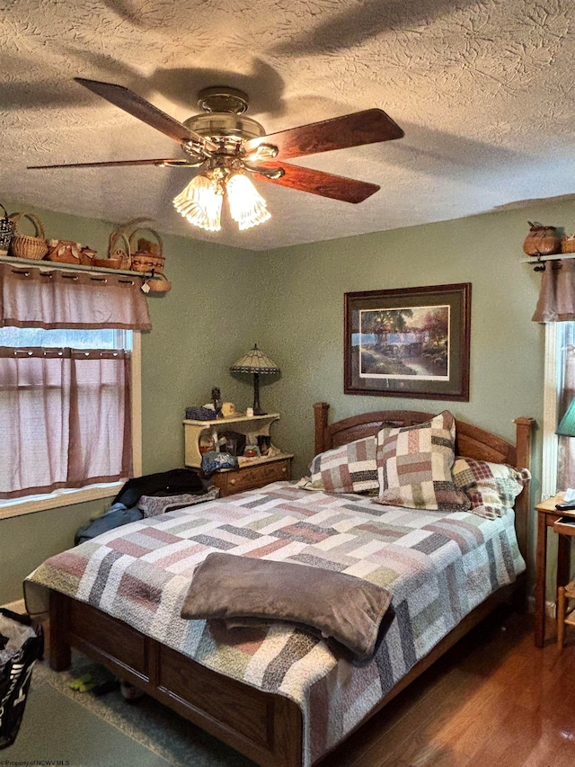 bedroom with a textured ceiling, dark hardwood / wood-style floors, and ceiling fan