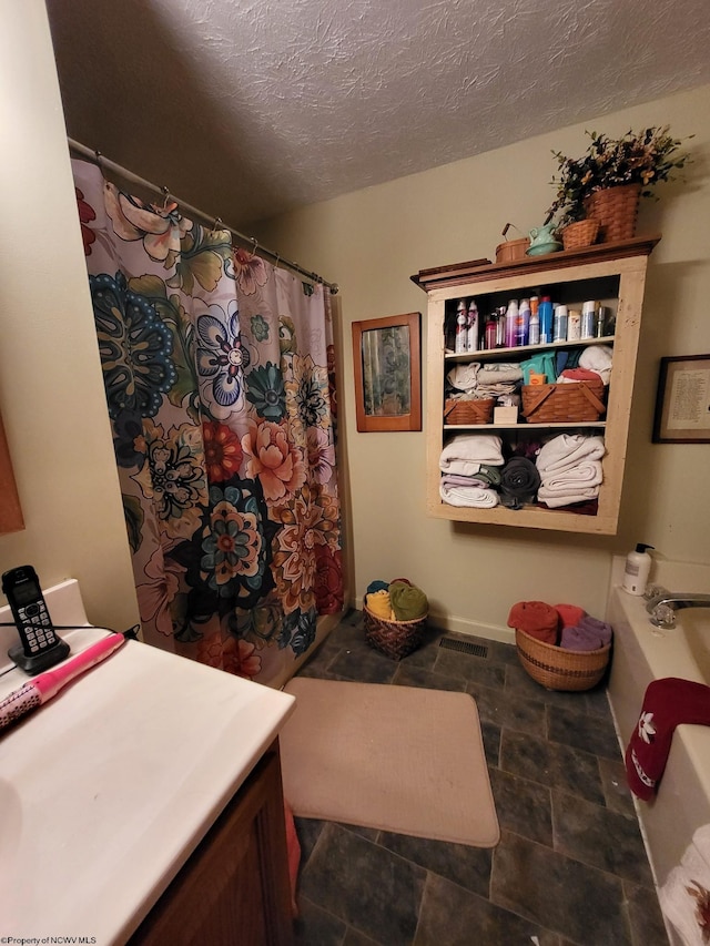 bathroom with vanity, curtained shower, and a textured ceiling