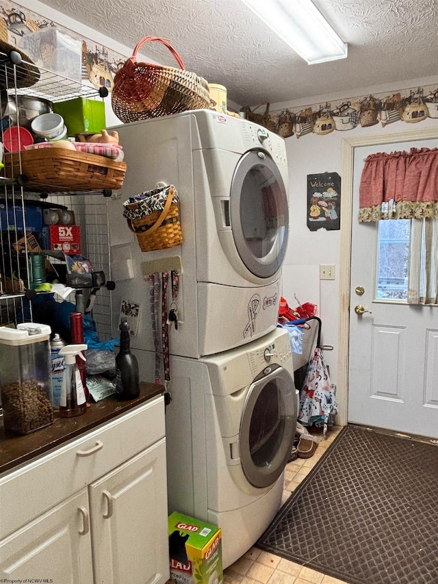 washroom featuring a textured ceiling, cabinets, and stacked washer / drying machine