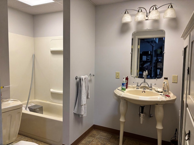 bathroom featuring toilet, a drop ceiling, and tub / shower combination