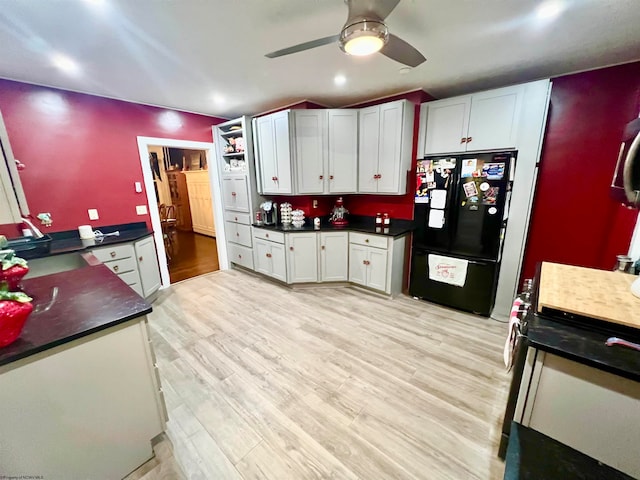 kitchen with white cabinets, black refrigerator, and light wood-type flooring