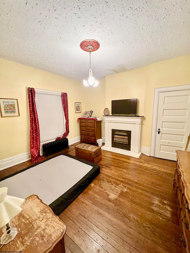 bedroom with a chandelier, a textured ceiling, and hardwood / wood-style flooring