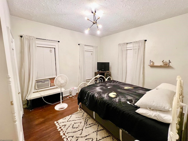 bedroom featuring dark hardwood / wood-style floors, cooling unit, a textured ceiling, and an inviting chandelier