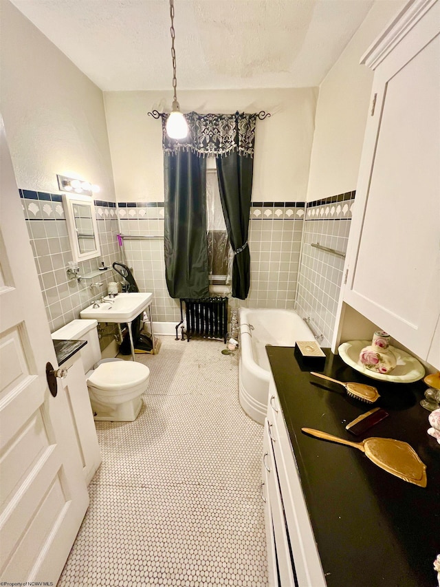 bathroom with tile patterned floors, a tub, tile walls, and toilet