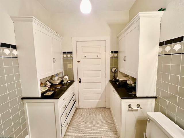 kitchen with white cabinets, light tile patterned floors, and tile walls