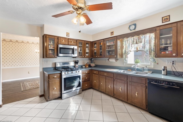 kitchen featuring sink, stainless steel appliances, backsplash, a textured ceiling, and light tile patterned floors