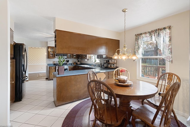 dining room featuring sink, light tile patterned flooring, and ceiling fan with notable chandelier