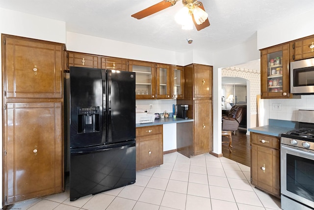 kitchen with appliances with stainless steel finishes, backsplash, light tile patterned floors, and ceiling fan