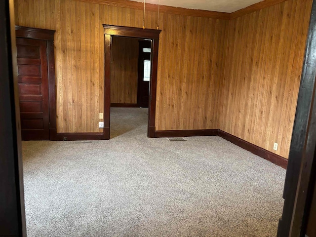 unfurnished room featuring carpet and wooden walls