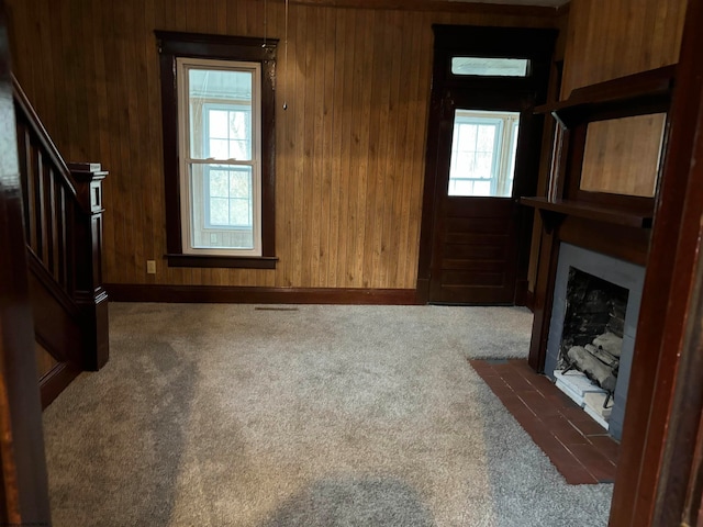 living room with wooden walls, plenty of natural light, and dark carpet