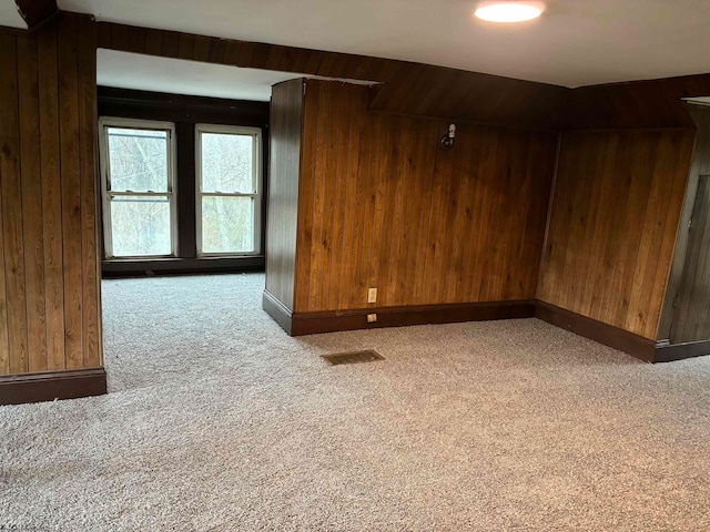 unfurnished room with carpet and wood walls