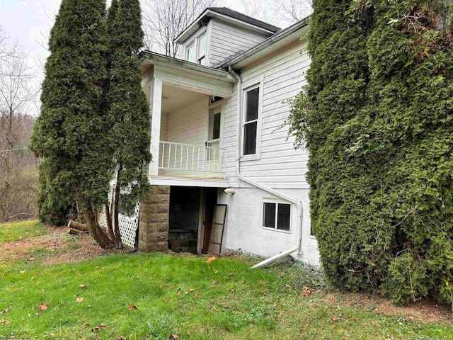 view of home's exterior with a balcony and a yard