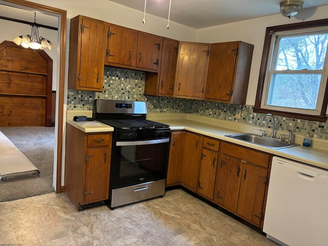 kitchen with backsplash, gas stove, white dishwasher, sink, and decorative light fixtures