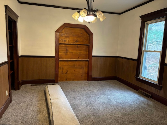 spare room with carpet, wood walls, and ornamental molding