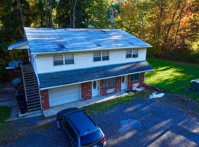 view of front of house featuring a garage, a porch, and a front lawn