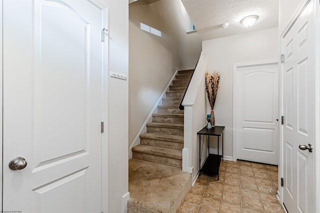 stairway featuring carpet flooring and a textured ceiling