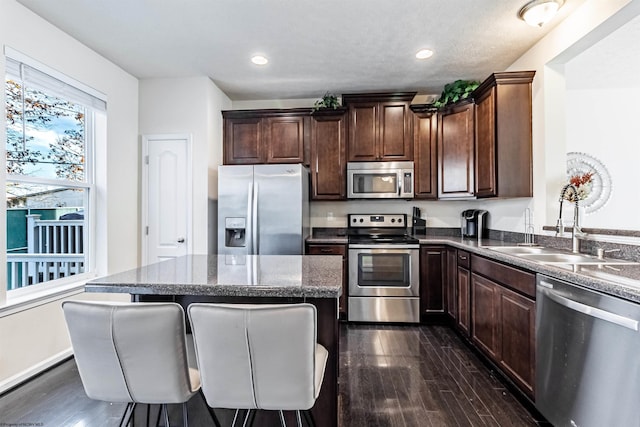 kitchen featuring sink, a breakfast bar area, dark hardwood / wood-style floors, a kitchen island, and stainless steel appliances